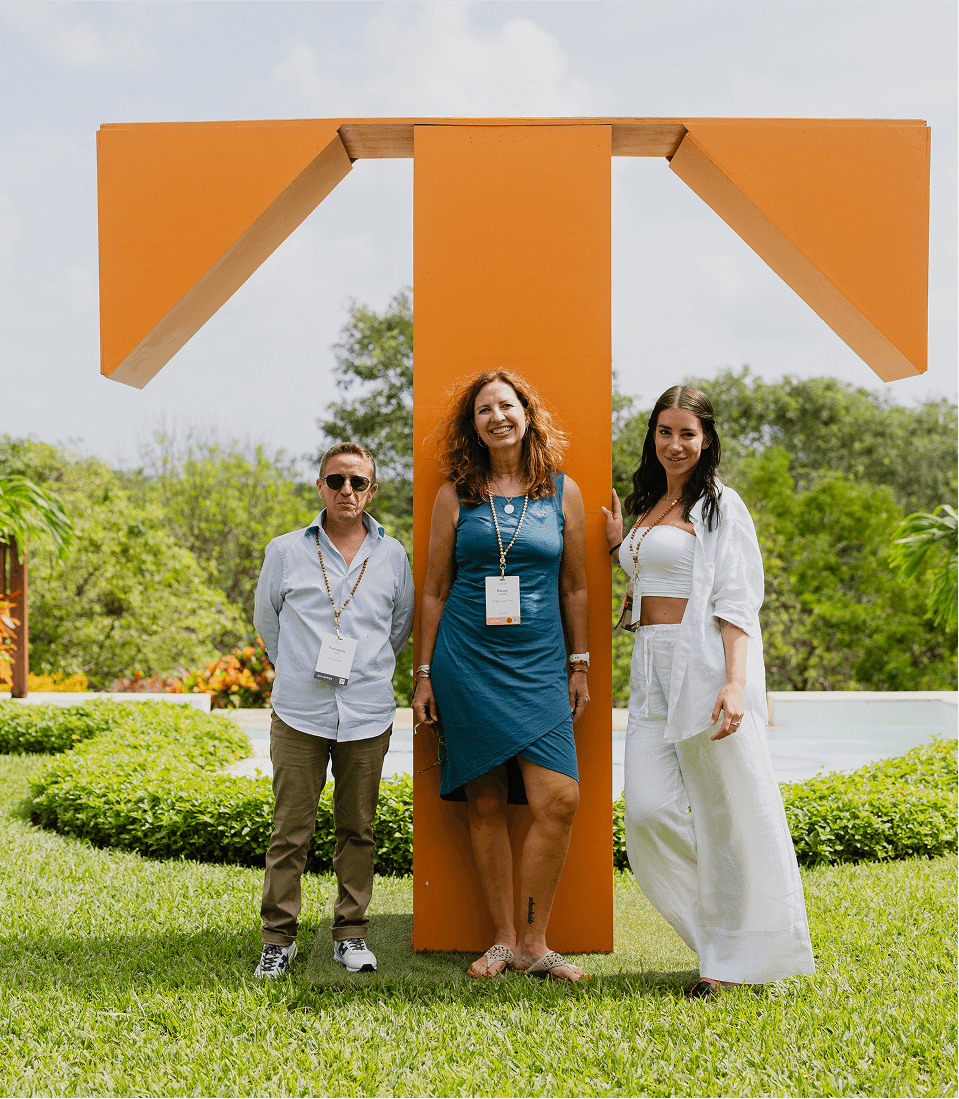 Three attendees posing in front of a giant orange TFest T