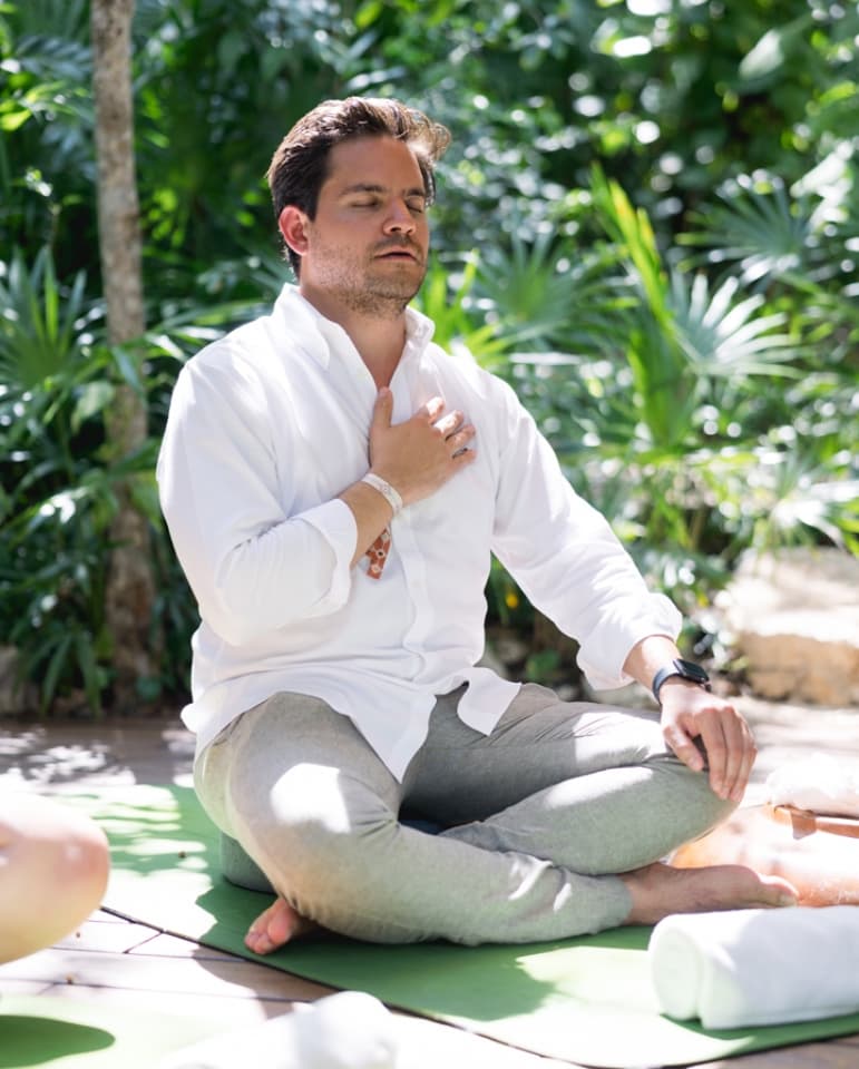 A guest meditating on a mat in the Mayakoba jungle