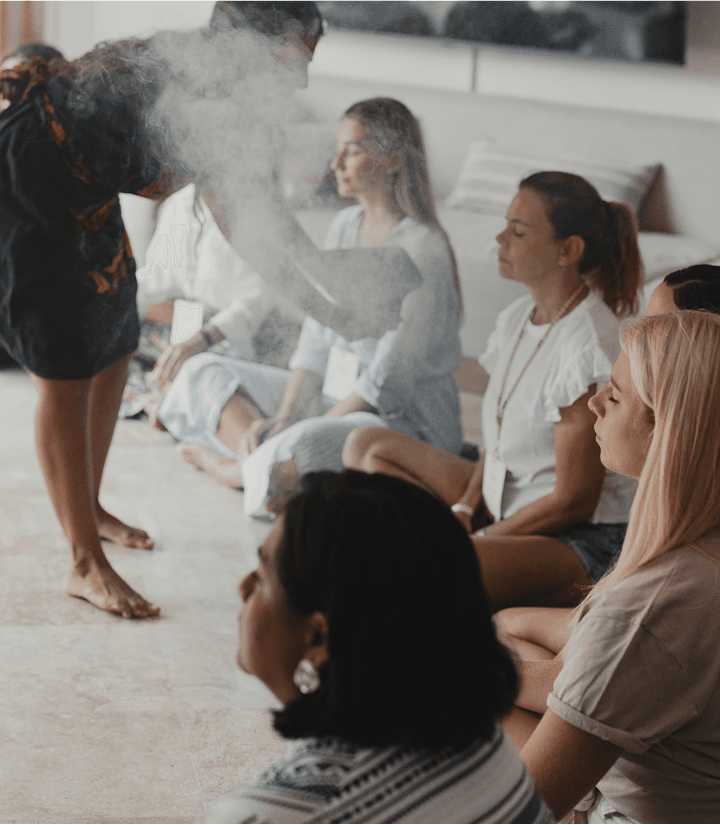 Attendees seated in meditation during a smoke-cleansing ceremony