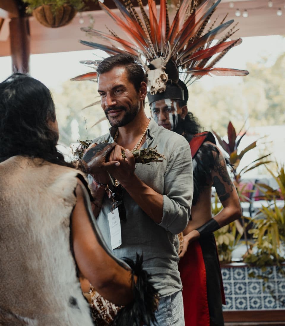 A guest greeted by a performer in a feathered headdress