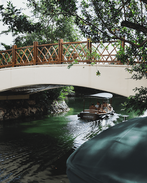 A boat passing under a bridge on Mayakoba’s jungle waterways