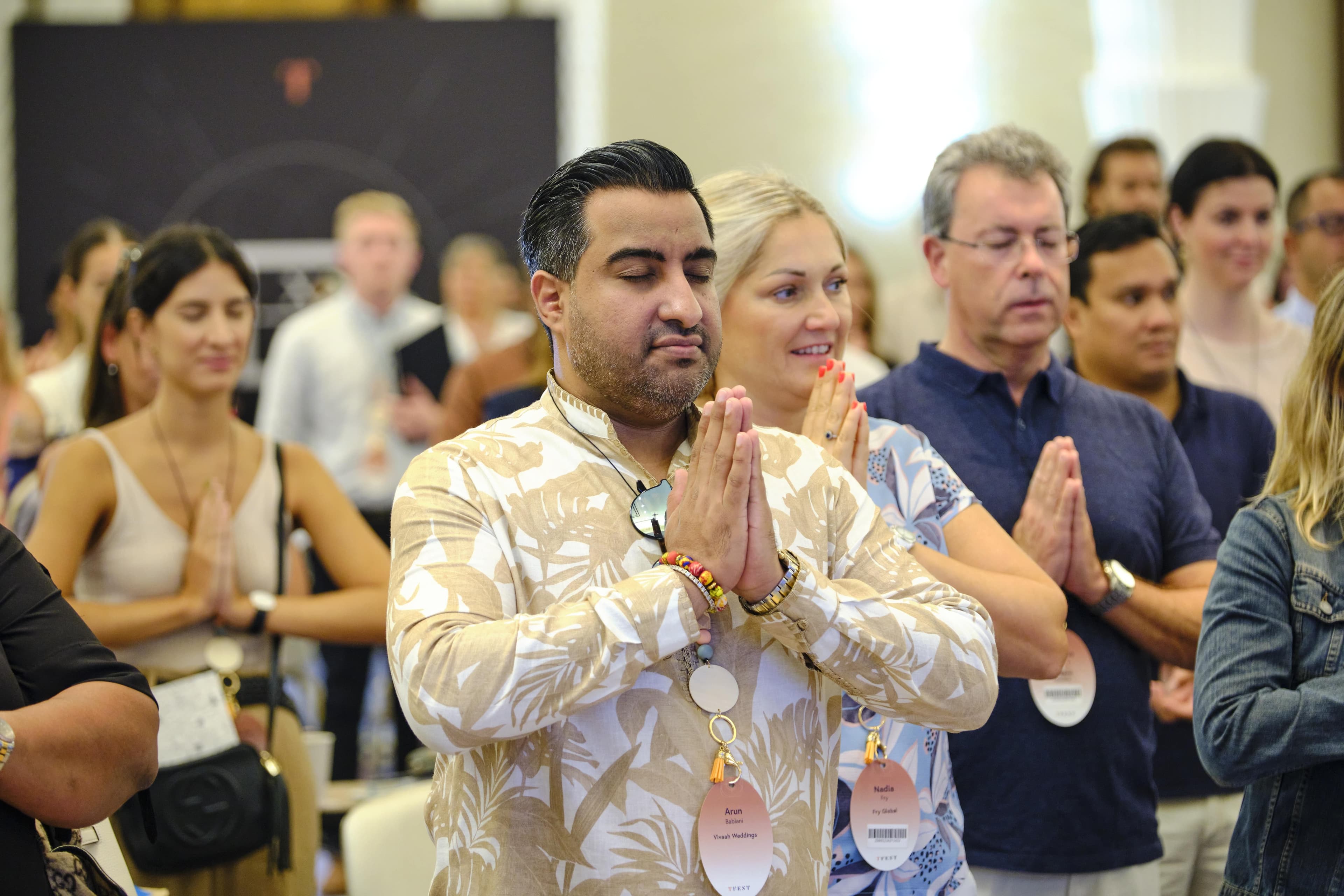 An attendee with hands pressed together in greeting
