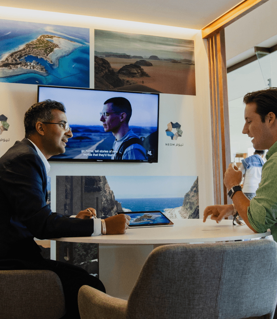 An exhibitor presenting on a large screen in a branded studio